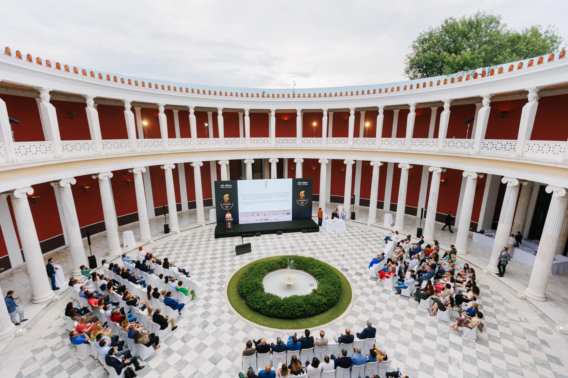 Ceremonia de ATHENA International Olive Oil Competition en un patio columnado